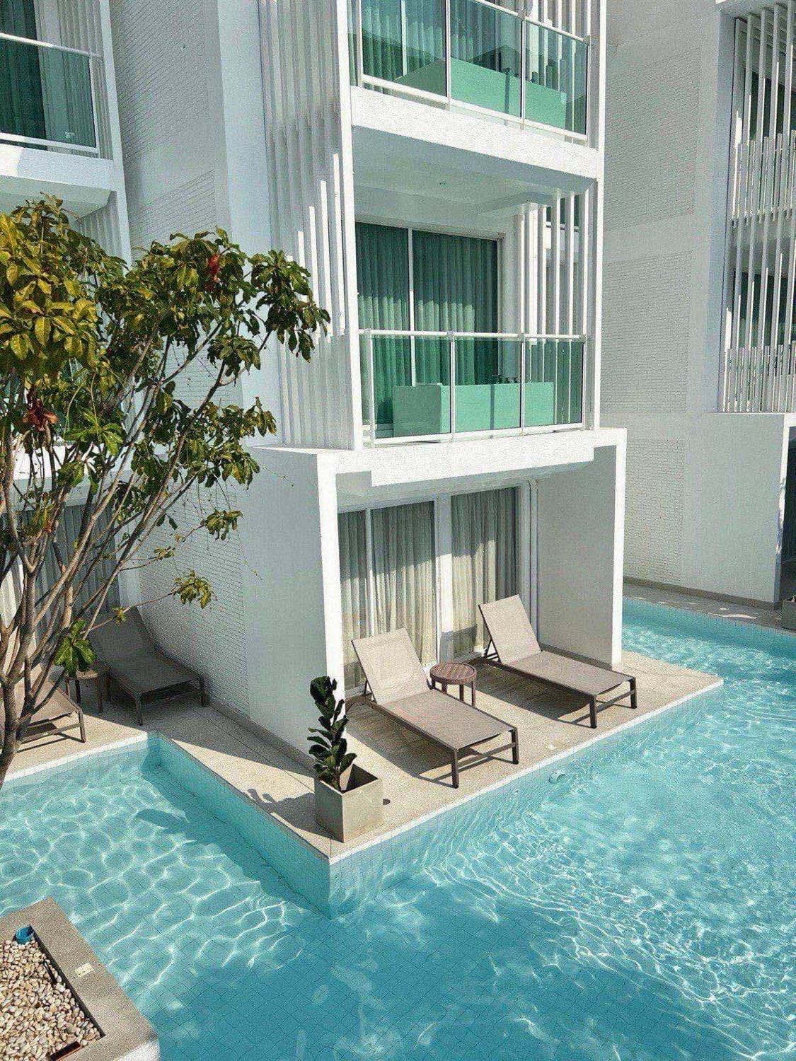 Condominium community pool and shared amenity area surrounded by lounge seating and a modern residential building